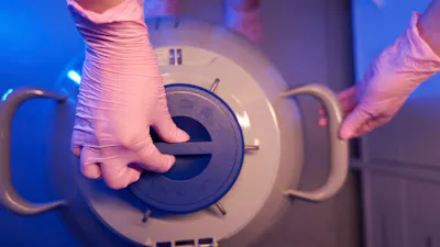 Cropped photo of researcher in protective gloves locking cover of liquid nitrogen dewar