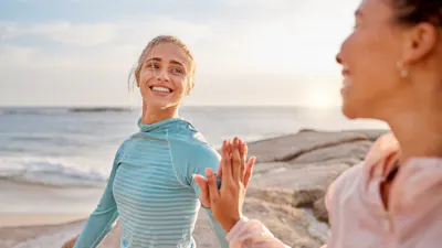 Fitness, touching hands and couple of friends at the beach for workout, training or exercise togeth.